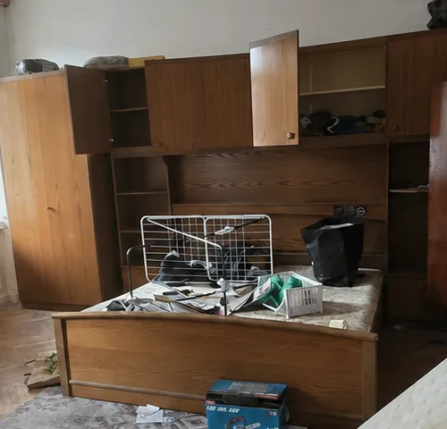 Offener Kleiderschrank und vollgestelltes Bett mit Kleidung, Kartons und losen Gegenständen in einem Schlafzimmer – Ausgangssituation vor der Entrümpelung mit Soforttermin in Leonding.