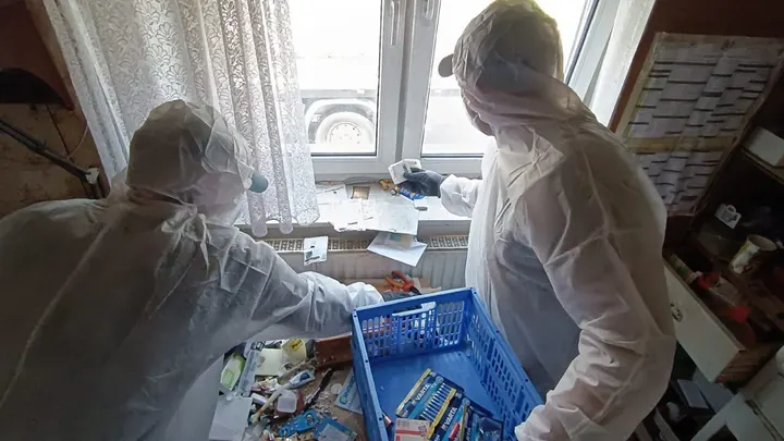 Messie Entrümpelung 1010 Wien Innere Stadt: zwei Mitarbeiter in Schutzanzügen räumen Gegenstände am Fenster in eine Kiste